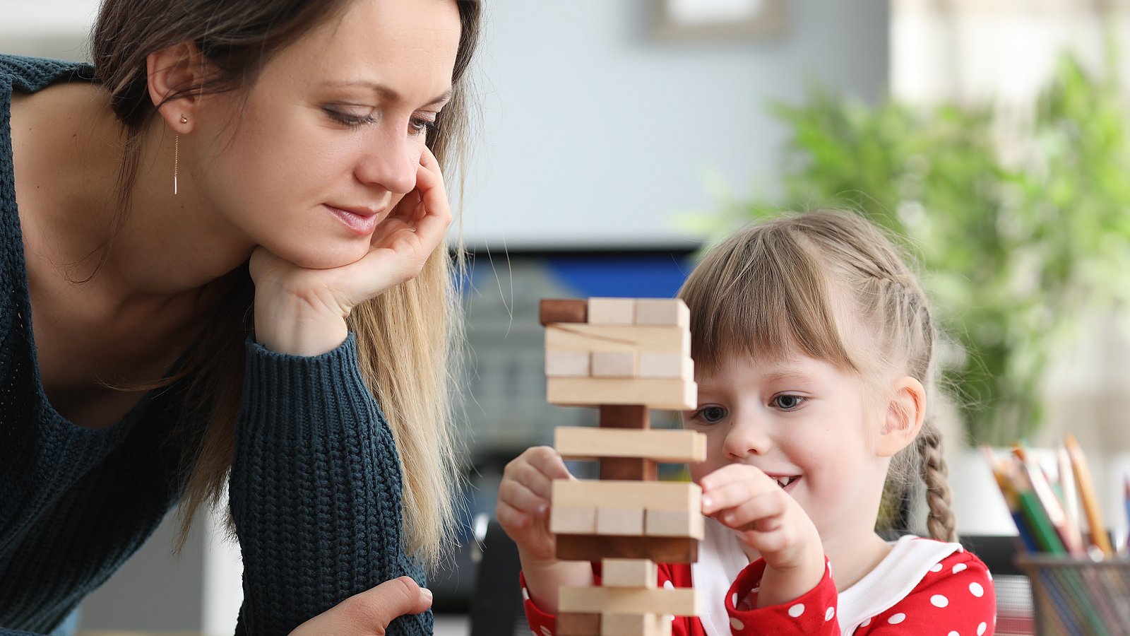 Kind und Frau bauen einen Holzspiel-Turm.