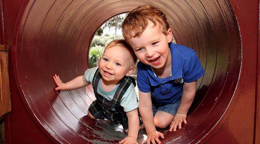 Ein kleiner Junge ist mit seinem etwas älteren Bruder in einem Spieltunnel. 