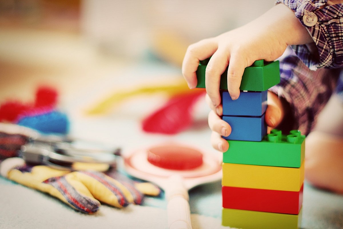 Kind baut mit großen Lego-Steinen einen Turm.