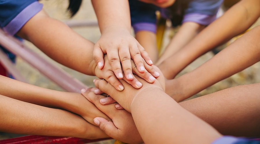 Viele Kinderhände im Kreis übereinander gelegt.