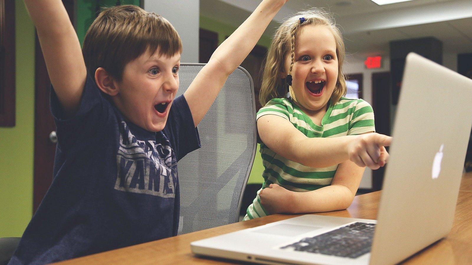 Kinder sitzen vor einem Laptop und freuen sich über einen Sieg.