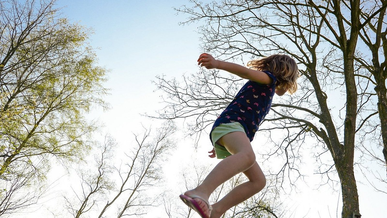 Ein Mädchen springt auf einem Trampolin. 