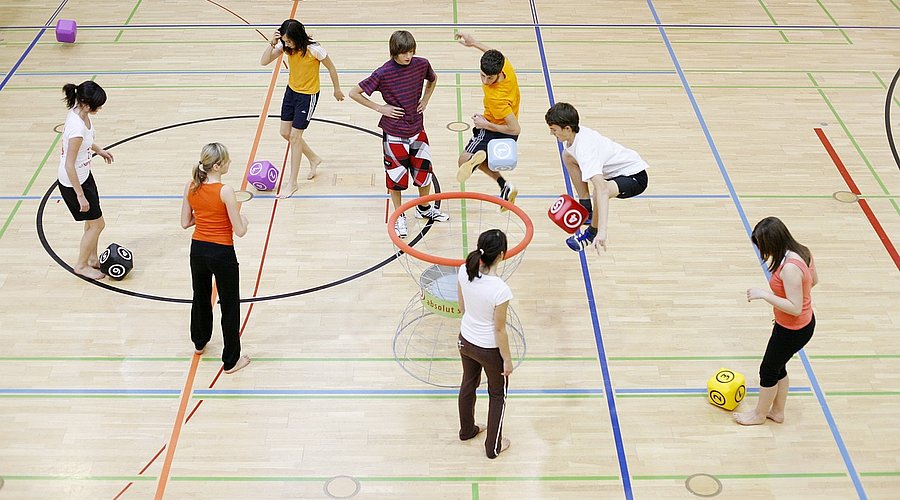 Schulklasse spielt Ballsport in der Sporthalle.