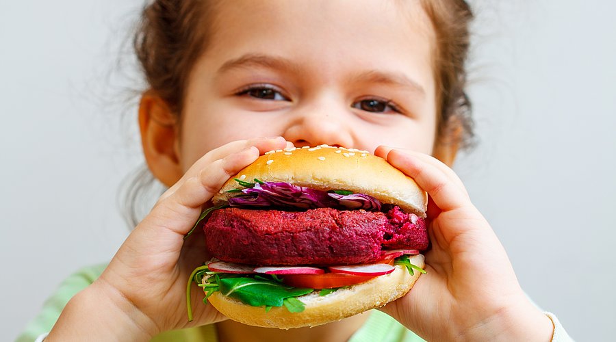 Kita-Kind beißt in Plant-based-Burger.