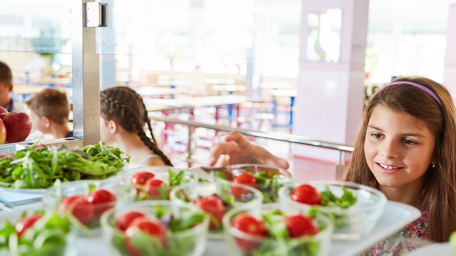 Jugendliche Schülerin bedient sich in der Mensa am Salatbuffet.