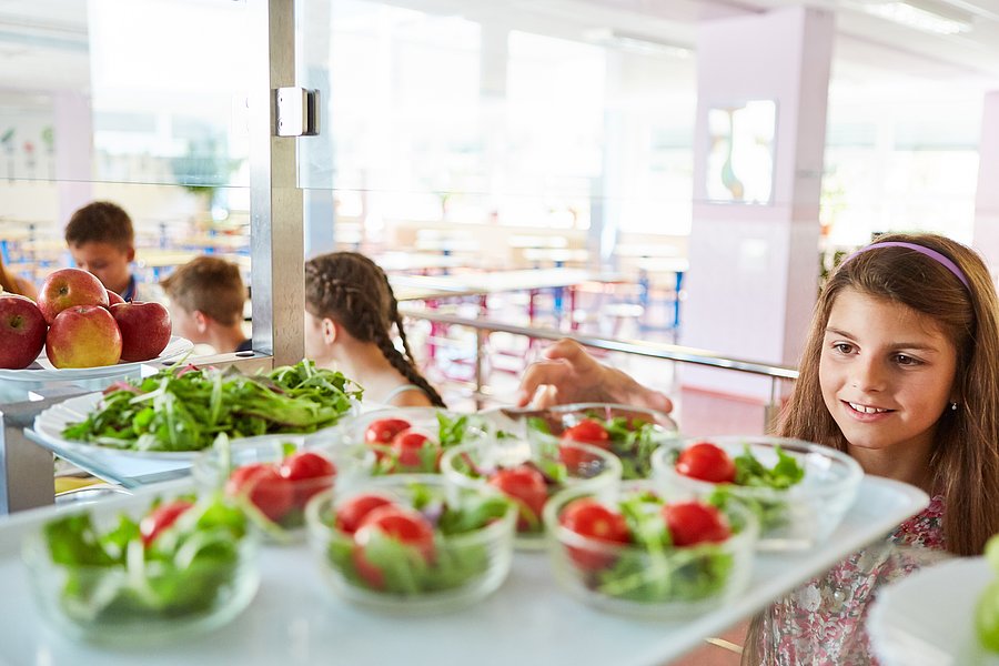 Jugendliche Schülerin bedient sich in der Mensa am Salatbuffet.