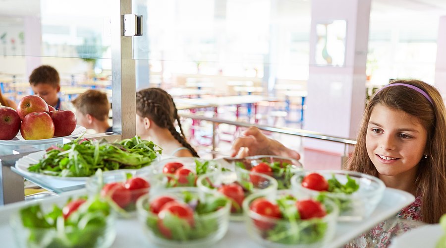 Jugendliche Schülerin bedient sich in der Mensa am Salatbuffet.