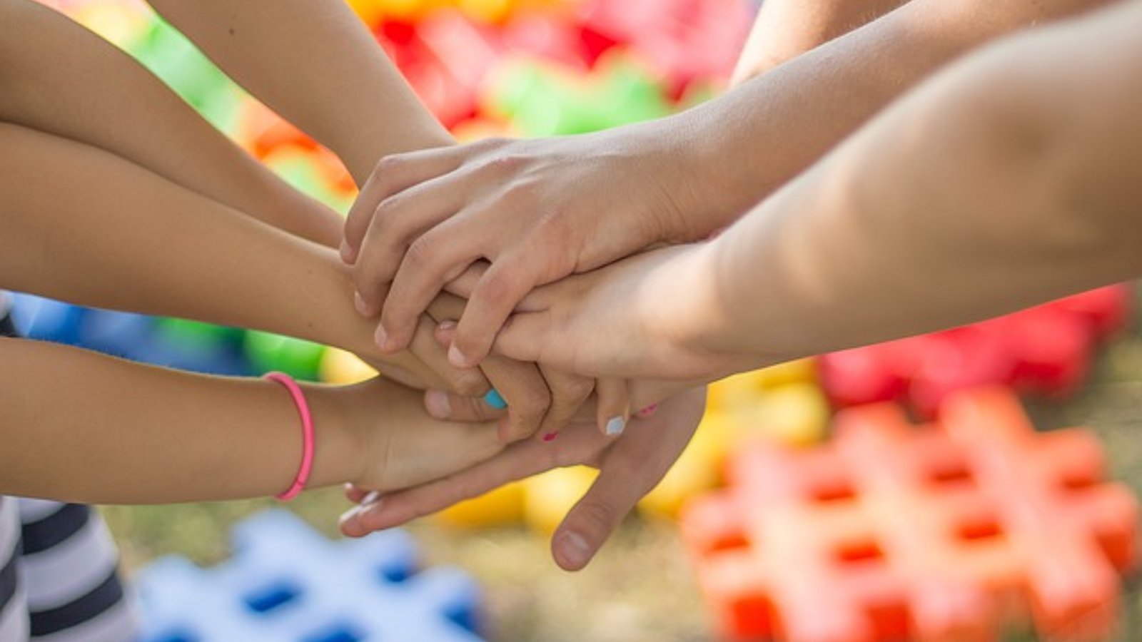 Kinder halten ihre Hände zum Zeichen des Miteinanders übereinander