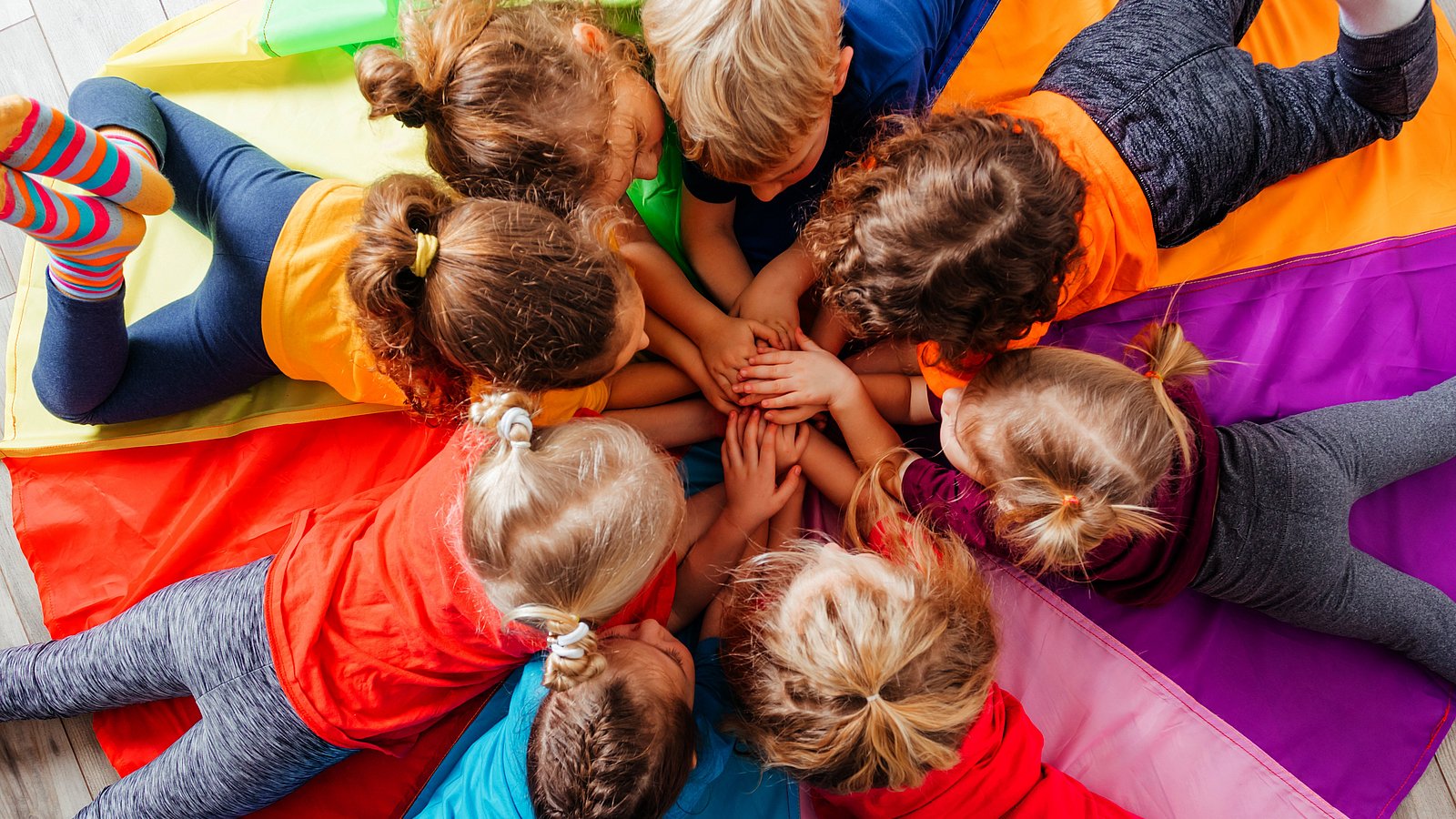 Kita-Kinder liegen bäuchlings im Kreis.