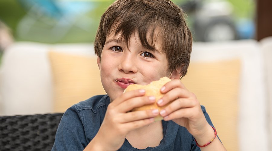 Schuljunge beißt herzhaft in ein Brötchen.