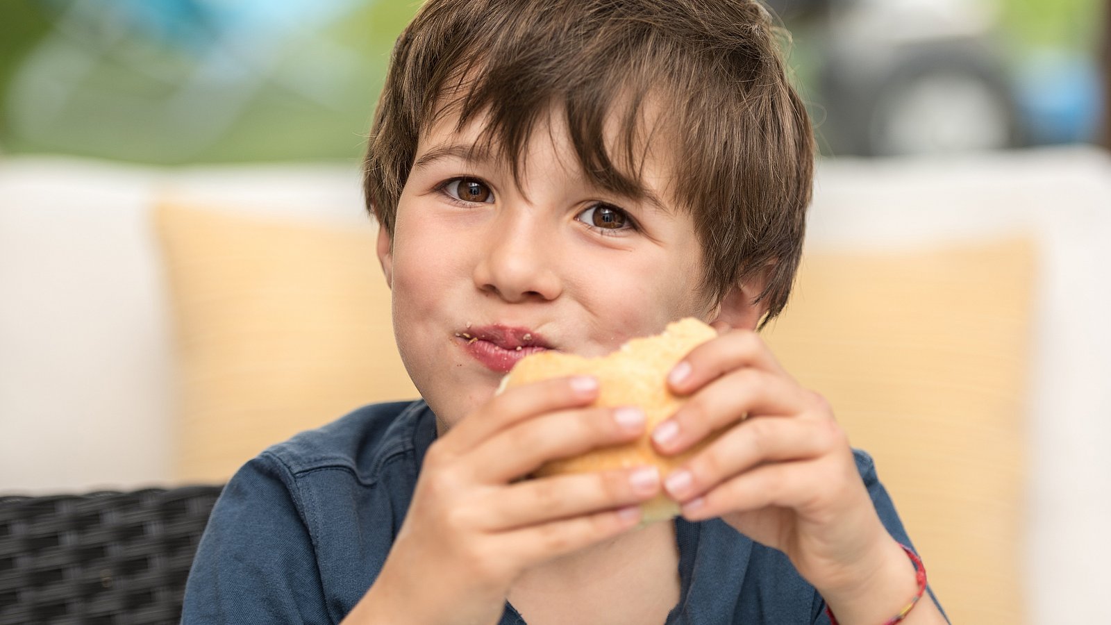 Schuljunge beißt herzhaft in ein Brötchen.