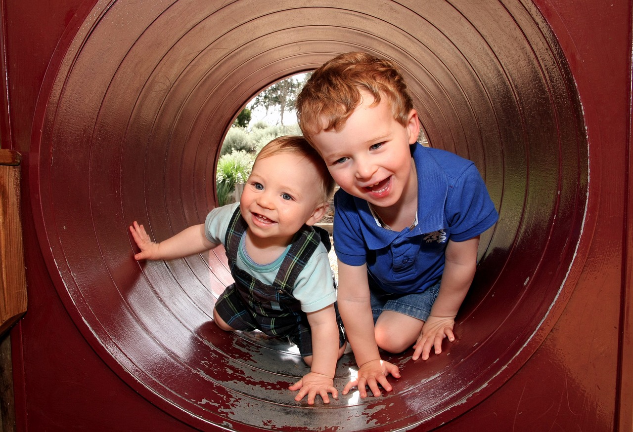 Ein kleiner Junge ist mit seinem etwas älteren Bruder in einem Spieltunnel. 